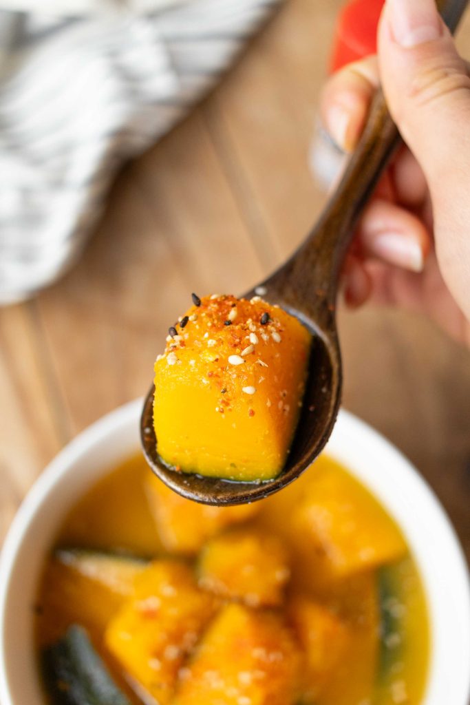 A wooden spoon with a mouthful of Kabocha Miso Soup.