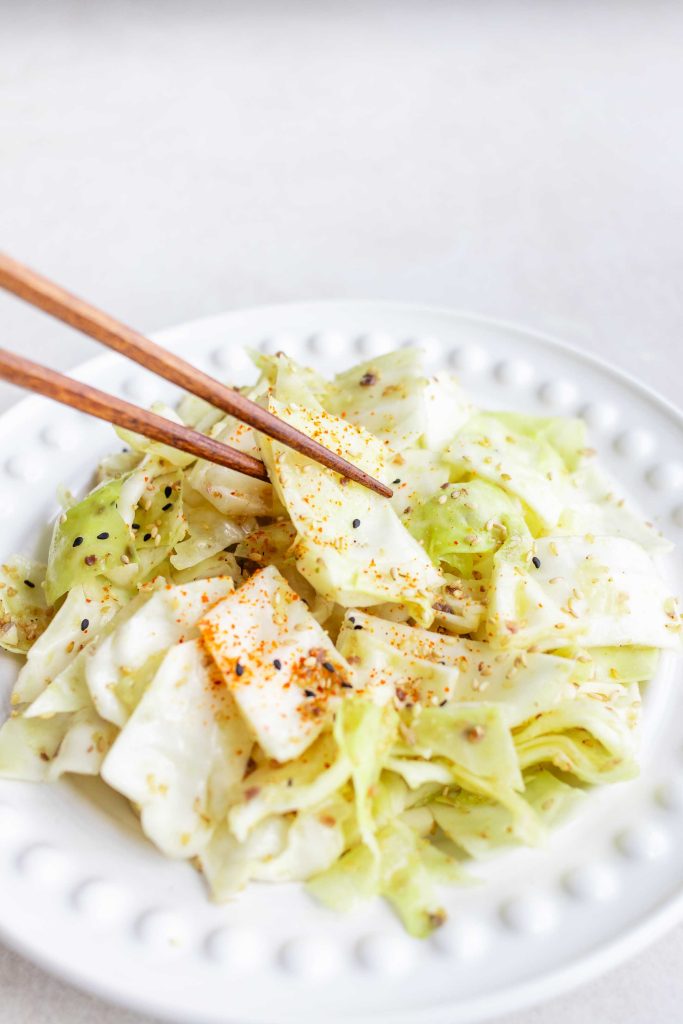 A plate of Yamitsuki Cabbage with some chopsticks grabbing a piece. 