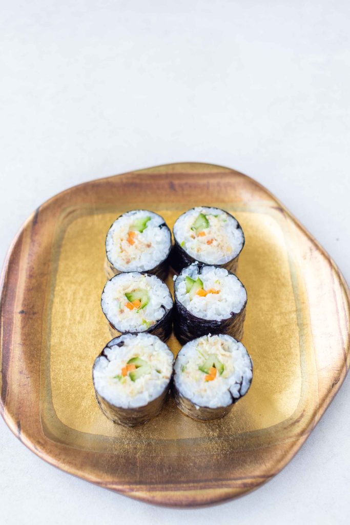 a plate of mackerel sushi on a gold plate.