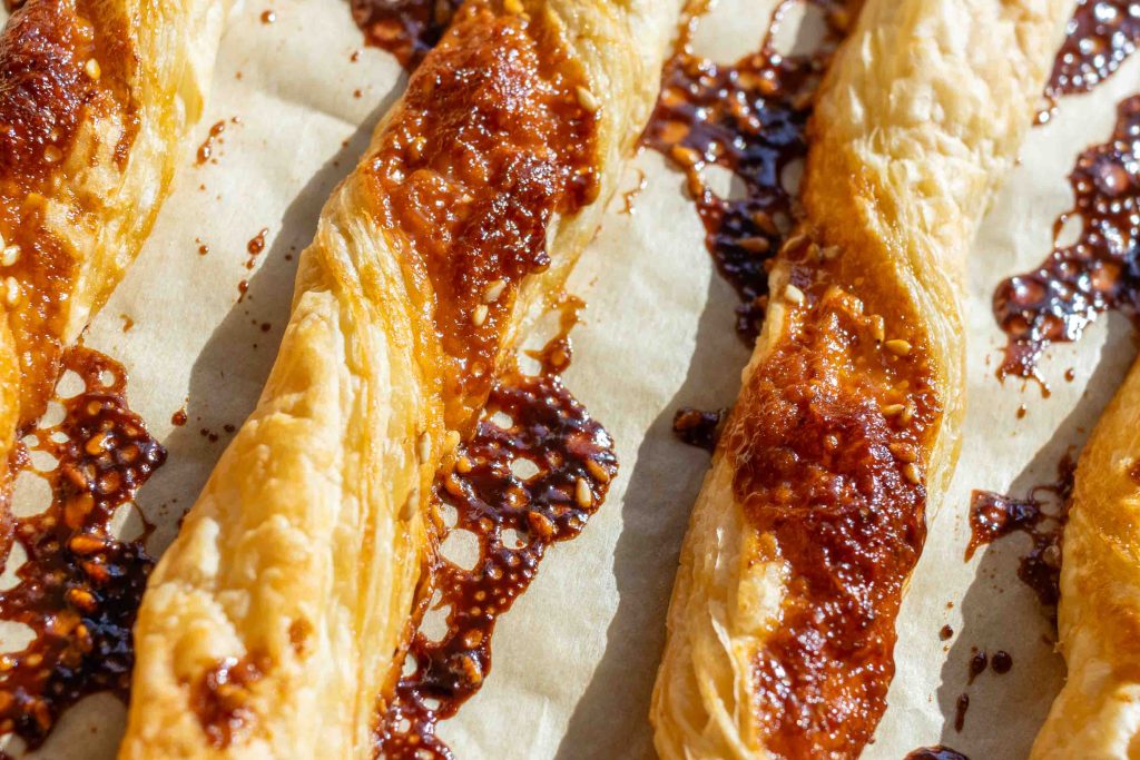 A close up of a sheet of puff pastry twists (miso and sesame flavour)
