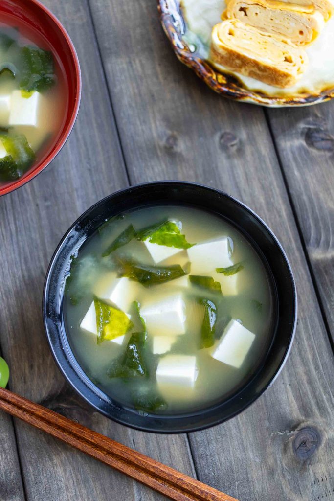 Two bowls of Tofu Miso Soup with a plate of Tamagoyaki in the top right corner. 