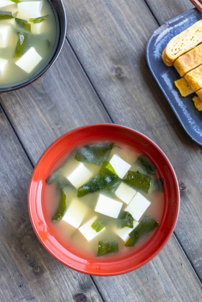 Two bowls of Tofu Miso Soup with a plate of Tamagoyaki in the top right corner.