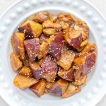 A plate of chicken and Japanese sweet potato, garnished with toasted white sesame seeds.