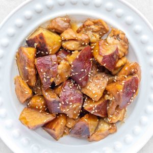 A plate of chicken and Japanese sweet potato, garnished with toasted white sesame seeds.