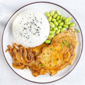 A plate of Japanese Ginger Pork (Shogayaki) with a side of rice and edamame beans