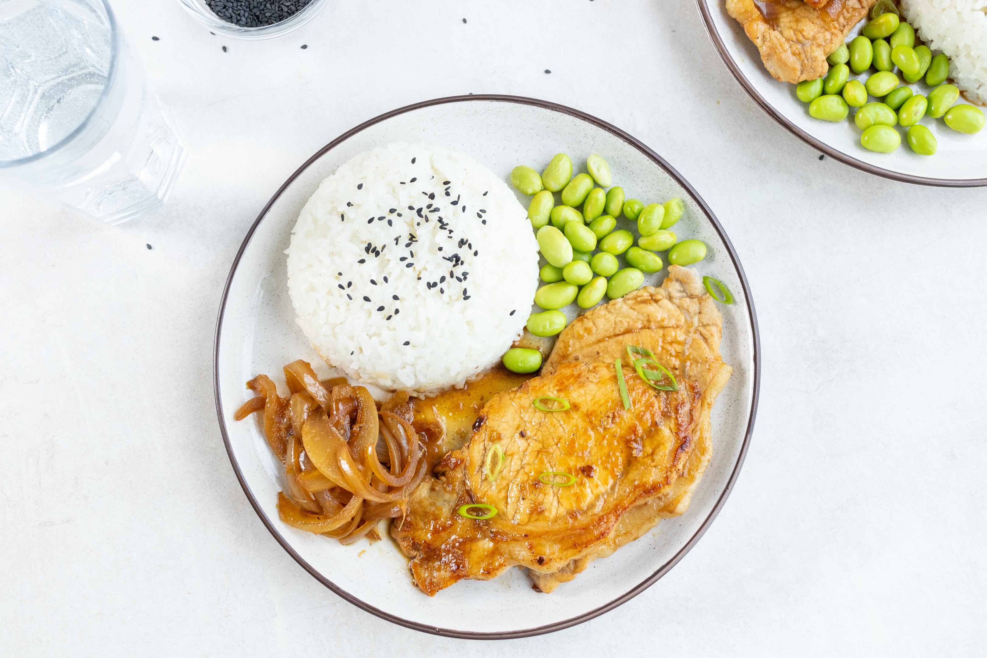 A plate of Japanese Ginger Pork (Shogayaki) with a side of rice and edamame beans