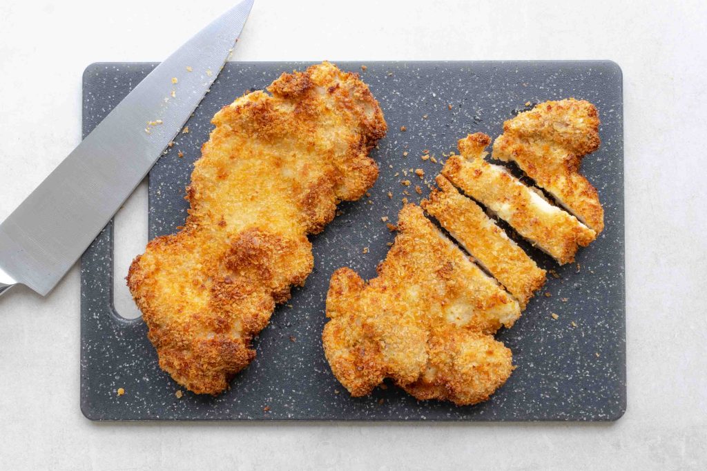 Two air fryer chicken katsu on a chopping board.