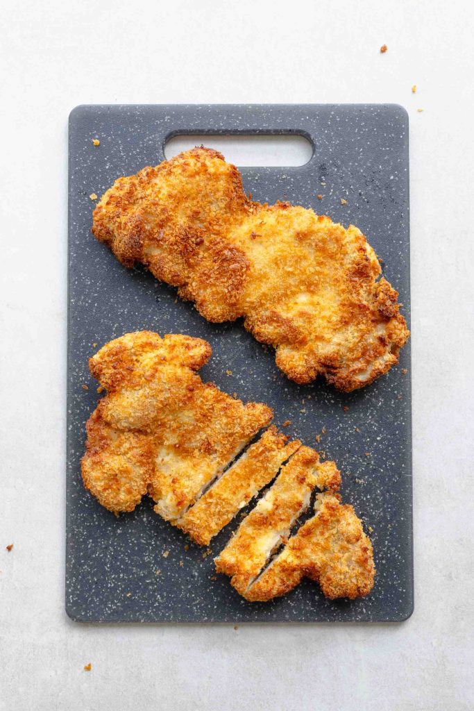 Two air fryer chicken katsu on a chopping board.