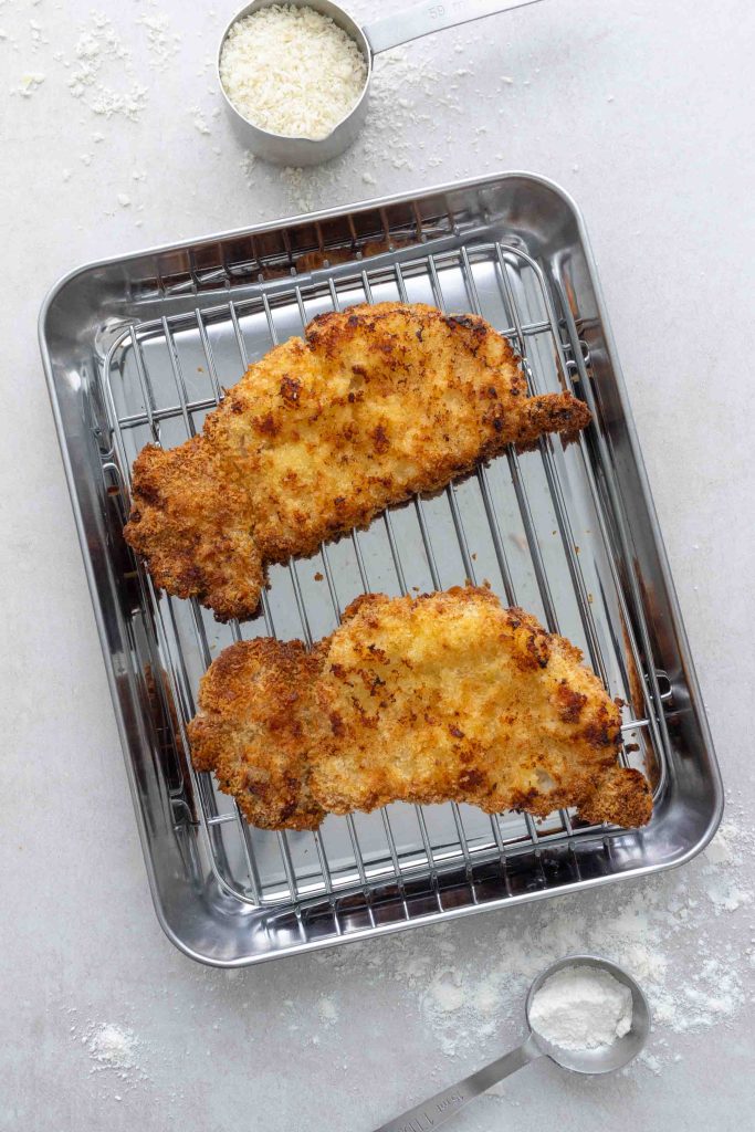 Two pieces of air fryer pork katsu on a silver cooling rack.