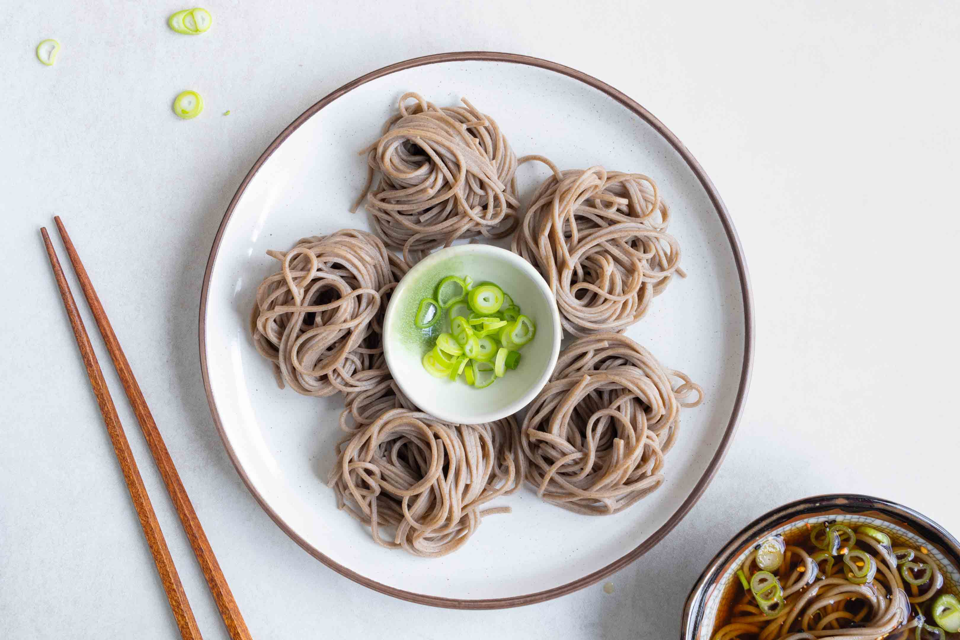 A plate of Zaru Soba with spring onion for garnish and some chopsticks to the right.