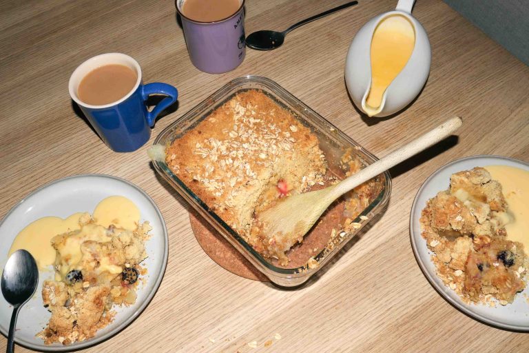 A dish of Kinako Mochi Apple Crumble surrounded by plates of crumble and custard.